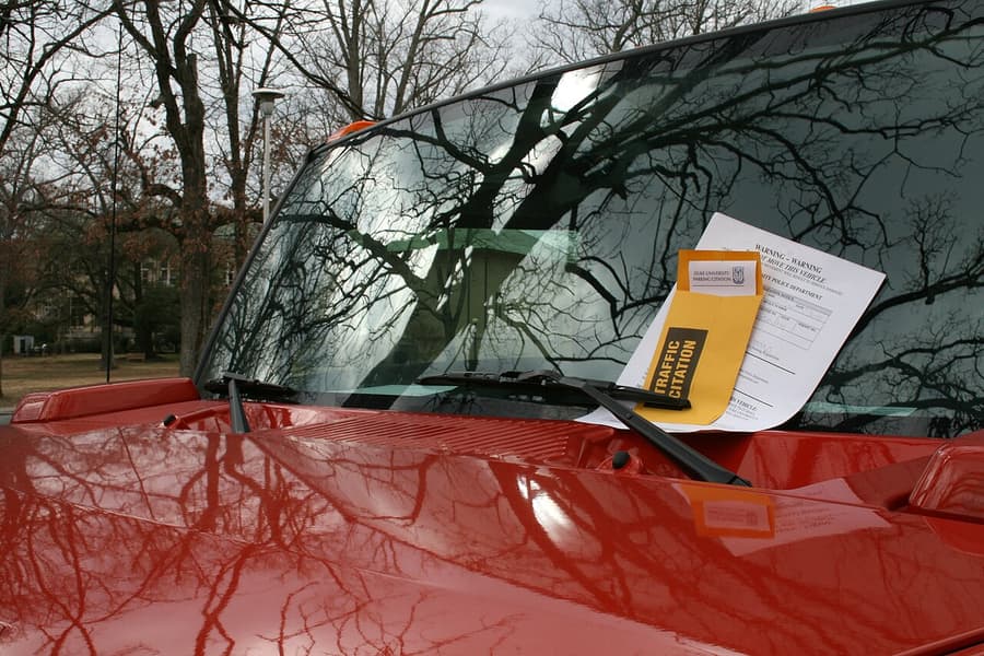 Aviso de multa bajo el limpiaparabrisas de un coche